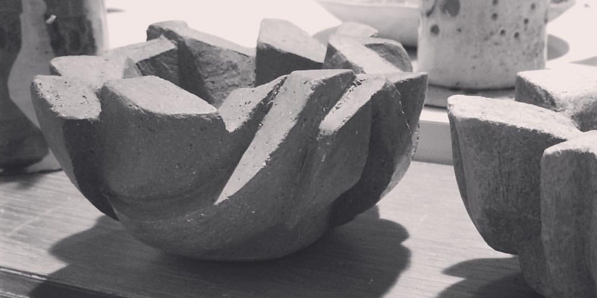 Photograph of a work in progress piece of pottery, it's a chunky carved bowl very deeply carved into a rough clay.